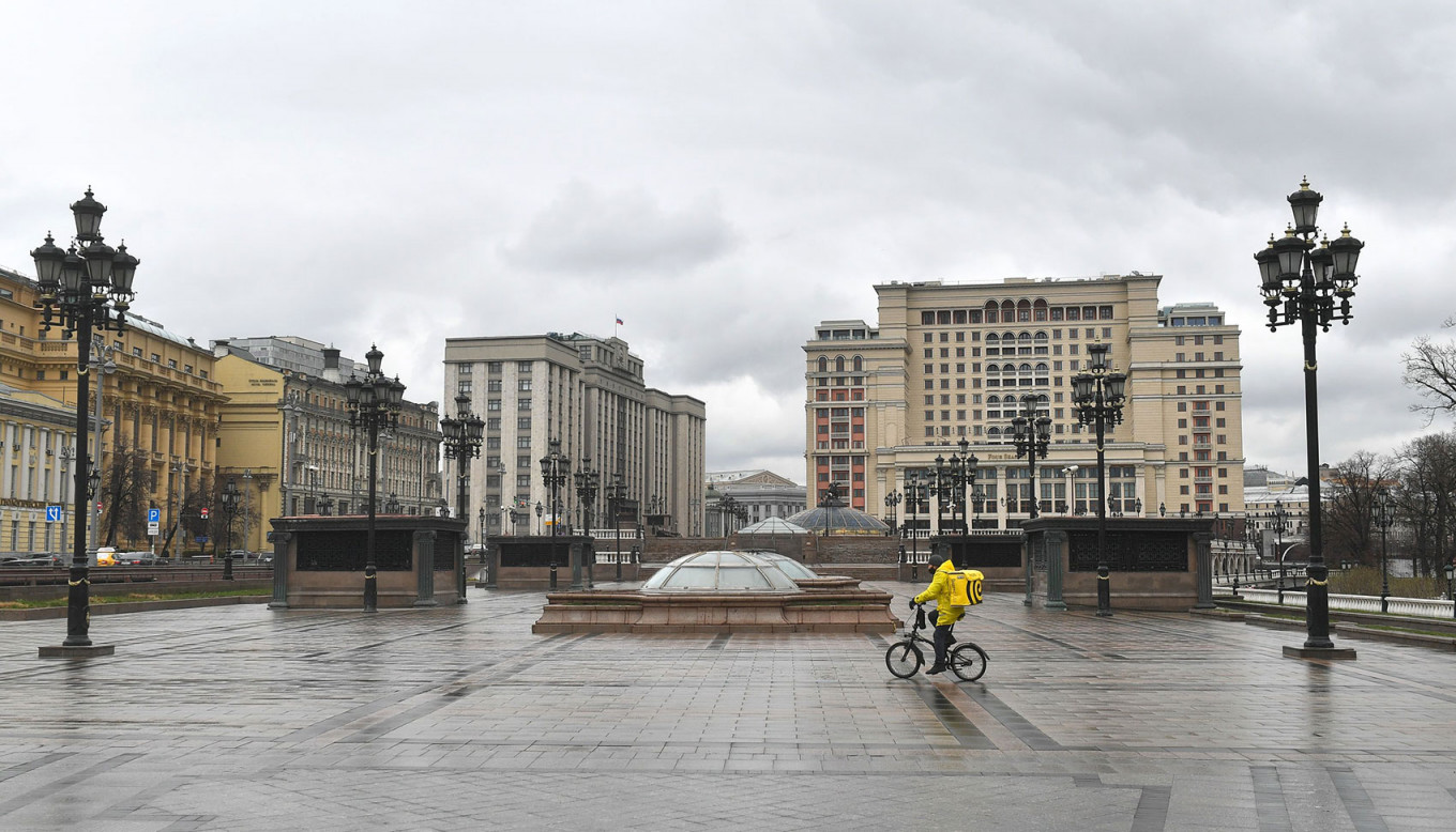 29 марта в Москве и Подмосковье ввели режим всеобщей самоизоляции. Покидать дом разрешалось только для похода на работу, в магазин или в больницу, а также чтобы выбросить мусор или погулять с собакой<br />
<br />
На фото: курьер «Яндекс.Еды» на Манежной площади в Москве